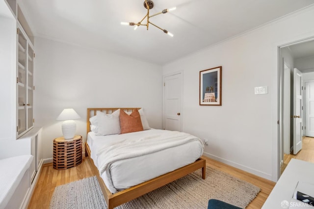 bedroom featuring an inviting chandelier, baseboards, and light wood-type flooring