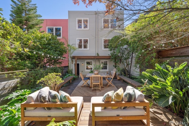 back of property with outdoor dining area, a wooden deck, and a chimney