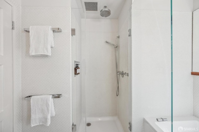 full bath featuring a tile shower and visible vents