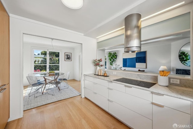 kitchen with light stone counters, white cabinets, light wood-style floors, and black electric cooktop