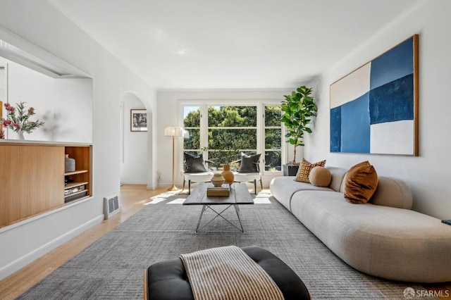 living area featuring visible vents, arched walkways, baseboards, and wood finished floors