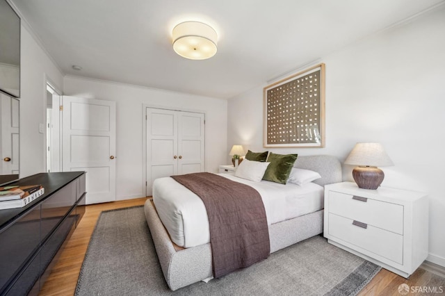 bedroom featuring a closet, light wood-style flooring, and baseboards