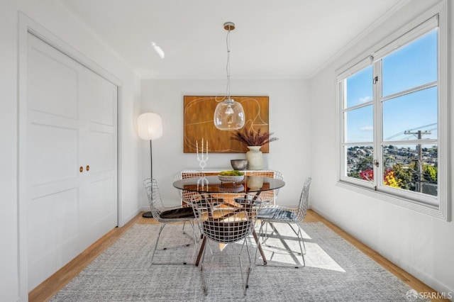 dining space with ornamental molding, baseboards, and wood finished floors