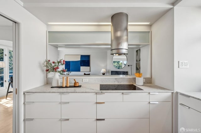 kitchen featuring open shelves, black electric stovetop, white cabinetry, and light stone countertops