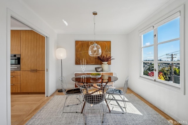 dining room with crown molding, light wood-style flooring, and baseboards