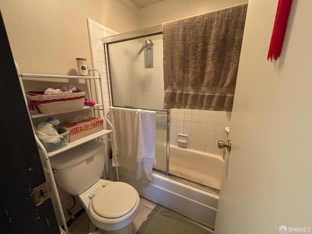 bathroom with tile patterned flooring, bath / shower combo with glass door, and toilet