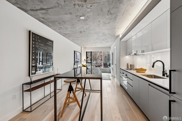 kitchen featuring light wood-type flooring, modern cabinets, a sink, and light countertops