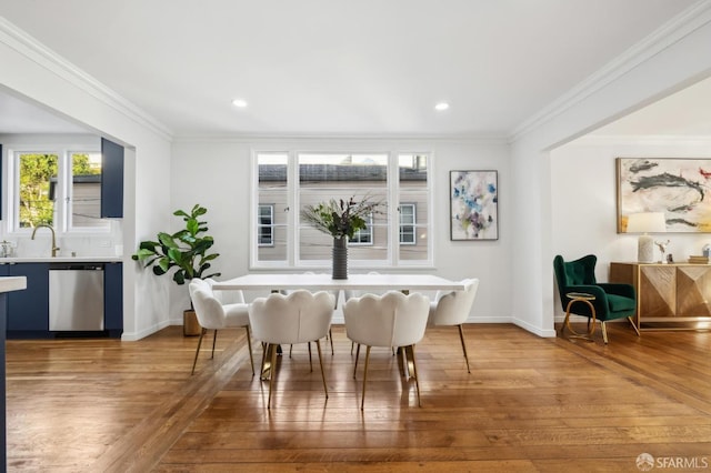 dining room with sink, hardwood / wood-style floors, and crown molding