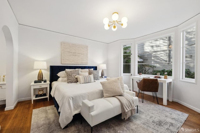 bedroom with a chandelier and dark wood-type flooring