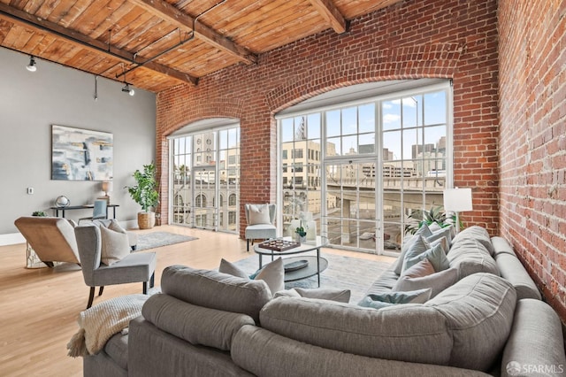 living room featuring light wood-style floors, wood ceiling, a city view, and brick wall