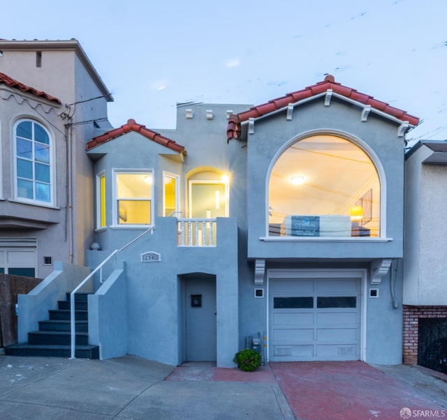 view of front facade featuring driveway, a garage, stairway, a tiled roof, and stucco siding