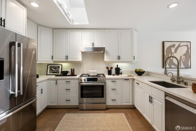 kitchen with stainless steel appliances, a sink, recessed lighting, under cabinet range hood, and white cabinets