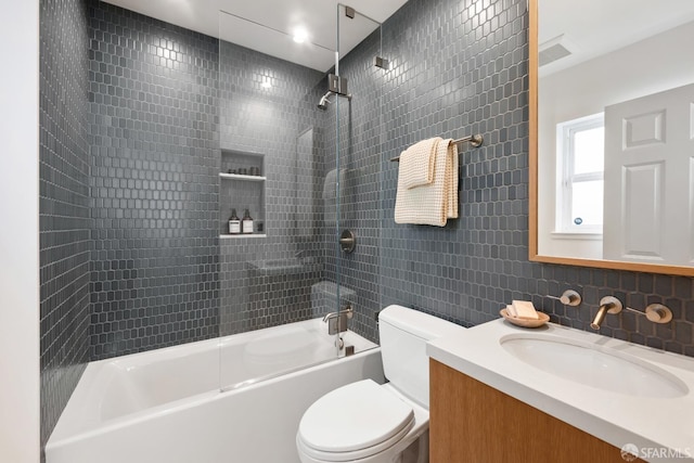 full bath featuring tub / shower combination, toilet, vanity, and tile walls