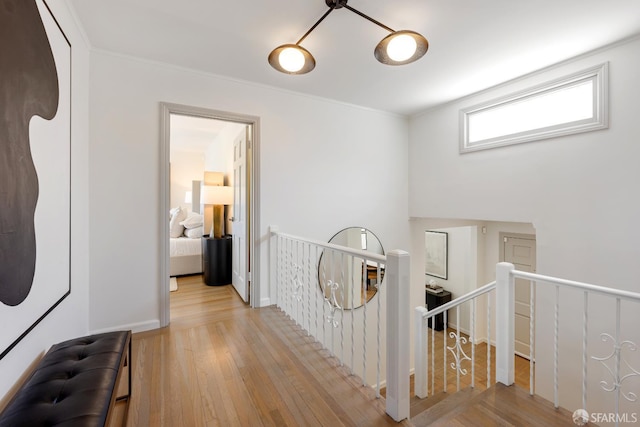 hall featuring an upstairs landing, wood finished floors, and ornamental molding