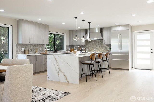 1098 Siler Pl, Berkeley, CA 94705 - kitchen featuring wall chimney range hood, gray cabinets, stainless steel built in fridge, light wood-style flooring, and decorative backsplash