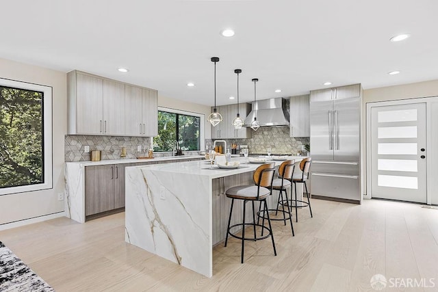 1098 Siler Pl, Berkeley, CA 94705 - kitchen with wall chimney exhaust hood, decorative backsplash, light wood-style floors, a kitchen breakfast bar, and recessed lighting