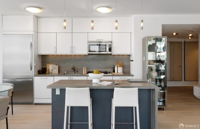 301 Main St Unit 34B, San Francisco, CA 94105 - kitchen featuring appliances with stainless steel finishes, tasteful backsplash, light wood-type flooring, and white cabinets