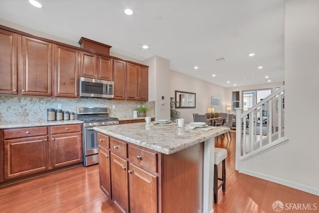 2702 Urbino Ct, San Jose, CA 95111 - kitchen featuring stainless steel appliances, a center island, a kitchen bar, light wood-style floors, and backsplash