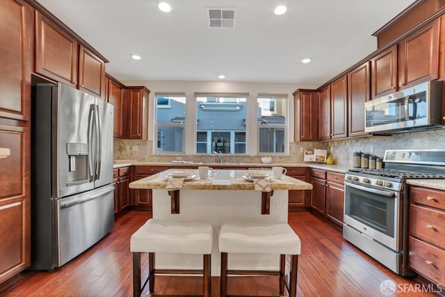 2702 Urbino Ct, San Jose, CA 95111 - kitchen featuring stainless steel appliances, a kitchen bar, dark wood-style floors, backsplash, and recessed lighting