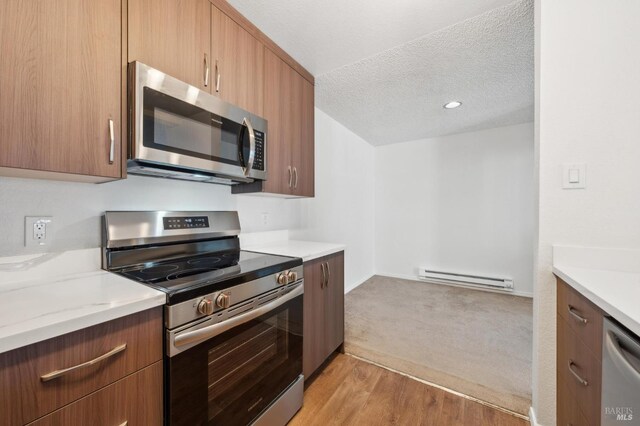 1201 Glen Cove Pkwy Unit 514, Vallejo, CA 94591 - kitchen featuring appliances with stainless steel finishes, a baseboard radiator, a textured ceiling, light wood-style floors, and light colored carpet