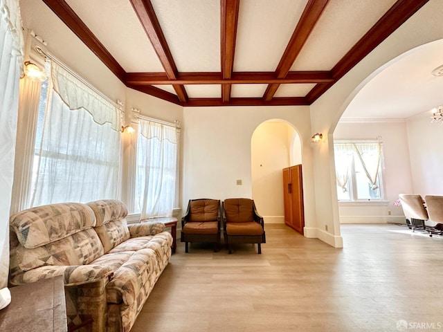 living area featuring arched walkways, light wood finished floors, coffered ceiling, beamed ceiling, and baseboards