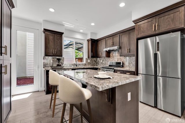 8534 Jetty Way, Newark, CA 94560 - kitchen with stainless steel appliances, dark brown cabinets, a breakfast bar area, decorative backsplash, and a kitchen island