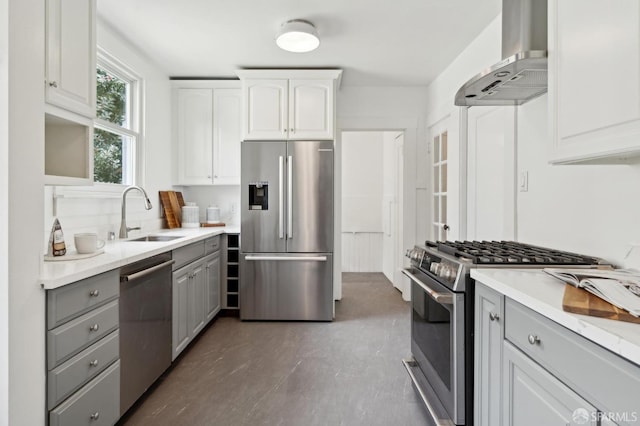 kitchen featuring white cabinets, a sink, gray cabinets, wall chimney exhaust hood, and stainless steel appliances