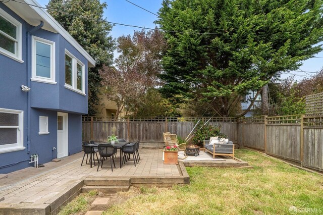 view of yard with a fenced backyard, outdoor dining area, and a fire pit