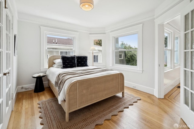 bedroom featuring baseboards, multiple windows, and light wood-type flooring