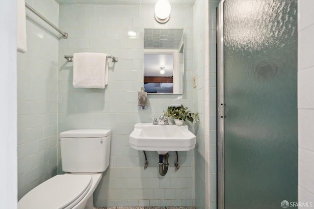 bathroom with toilet, tile walls, a sink, and a stall shower