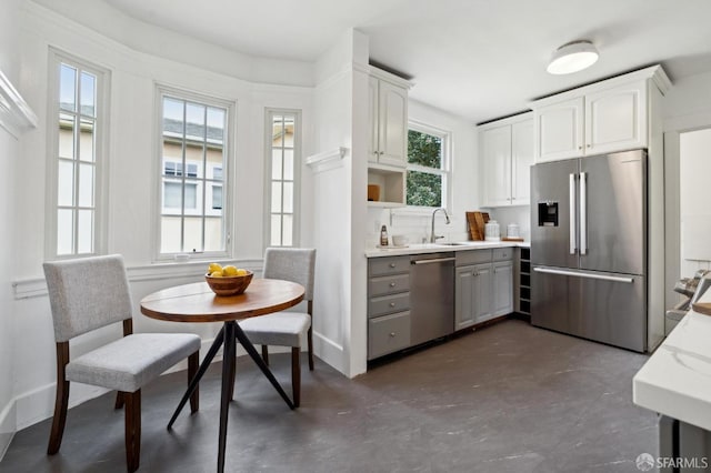 kitchen featuring concrete flooring, white cabinets, gray cabinets, and stainless steel appliances