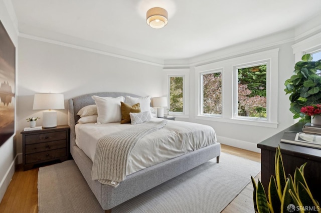 bedroom featuring baseboards, ornamental molding, and light wood-type flooring