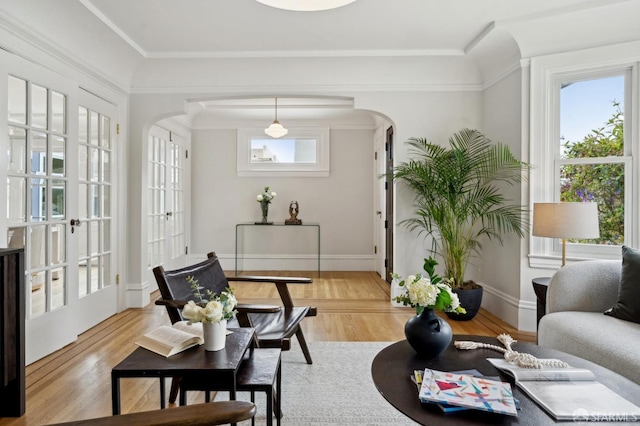living room featuring arched walkways, baseboards, and light wood-style flooring
