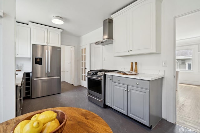 kitchen featuring white cabinets, stainless steel appliances, gray cabinetry, and wall chimney exhaust hood