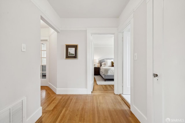 corridor featuring baseboards, visible vents, and light wood-type flooring