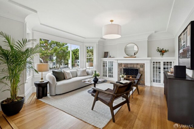 living area featuring light wood-style floors, crown molding, and a fireplace