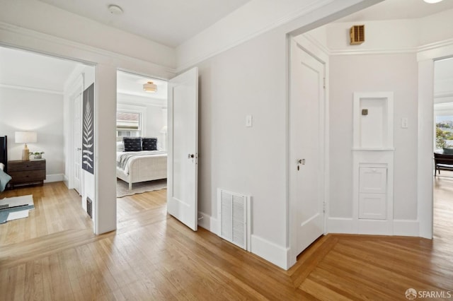 corridor featuring visible vents, baseboards, and light wood-type flooring