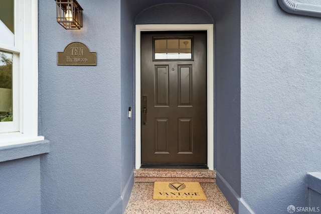 doorway to property featuring stucco siding