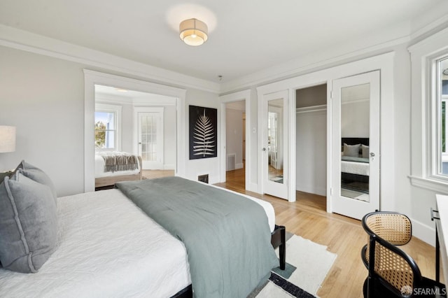 bedroom with light wood-style floors, visible vents, and french doors