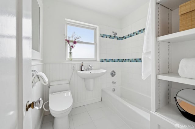 full bath featuring wainscoting, a sink, tile patterned floors, toilet, and tub / shower combination