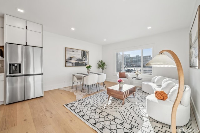 living room featuring light wood-style floors, a view of city, baseboards, and recessed lighting