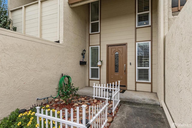 property entrance featuring a porch, fence, and stucco siding