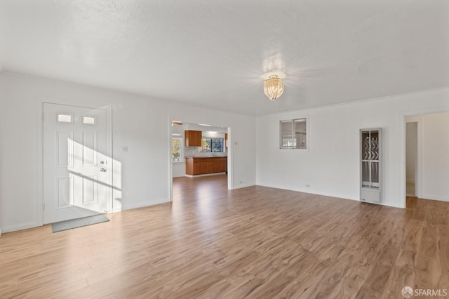 unfurnished living room with a notable chandelier and light wood-type flooring