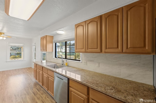 kitchen with sink, light hardwood / wood-style flooring, dishwasher, backsplash, and light stone countertops