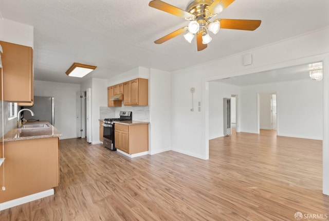 kitchen with sink, ceiling fan, appliances with stainless steel finishes, tasteful backsplash, and light wood-type flooring