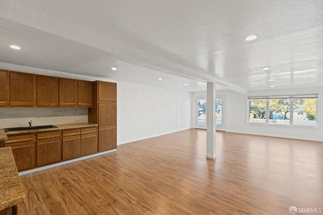 unfurnished living room with light hardwood / wood-style floors, sink, and a textured ceiling