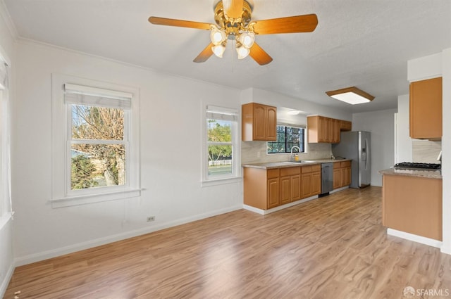 kitchen featuring sink, ceiling fan, appliances with stainless steel finishes, light hardwood / wood-style floors, and decorative backsplash