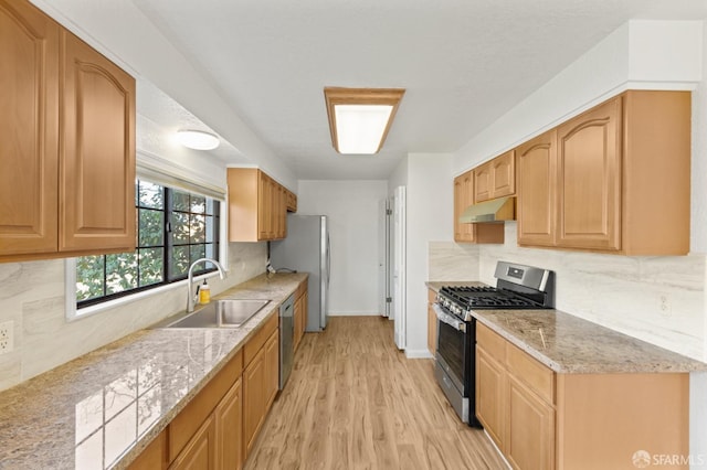 kitchen with light stone counters, sink, light hardwood / wood-style floors, and appliances with stainless steel finishes