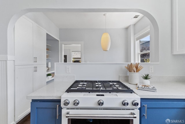 kitchen with pendant lighting, blue cabinetry, white cabinetry, light stone countertops, and gas stove