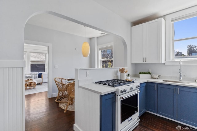 kitchen featuring pendant lighting, high end stove, blue cabinets, white cabinetry, and sink